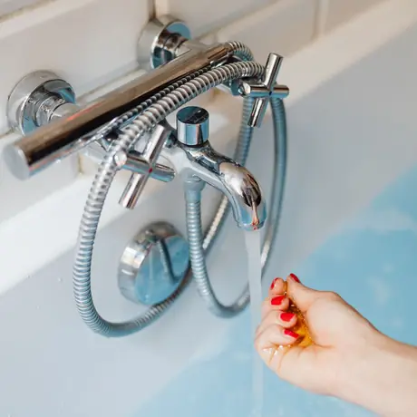 Una mano probando la temperatura del agua que sale de la llave